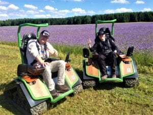 Zwei Personen auf Spezialfahrzeugen vor Lavendelfeld.