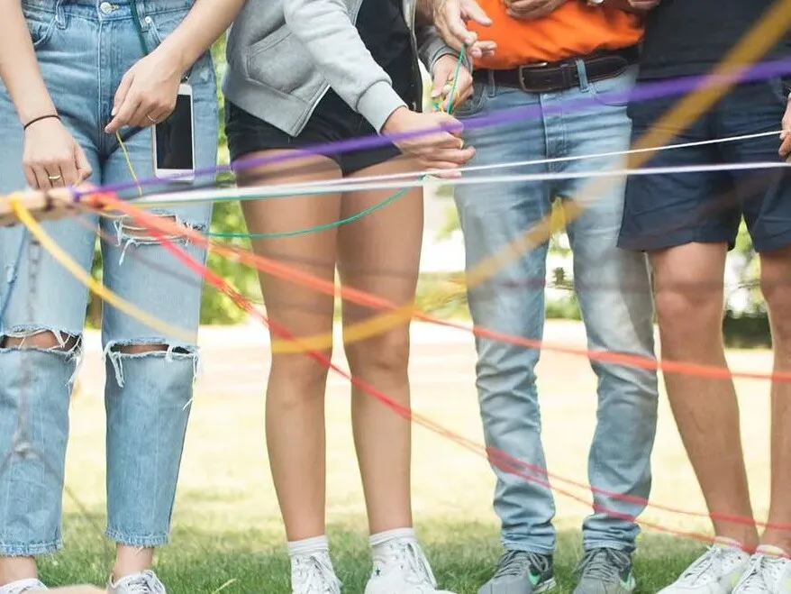 Personengruppe hält bunte Bänder im Freien