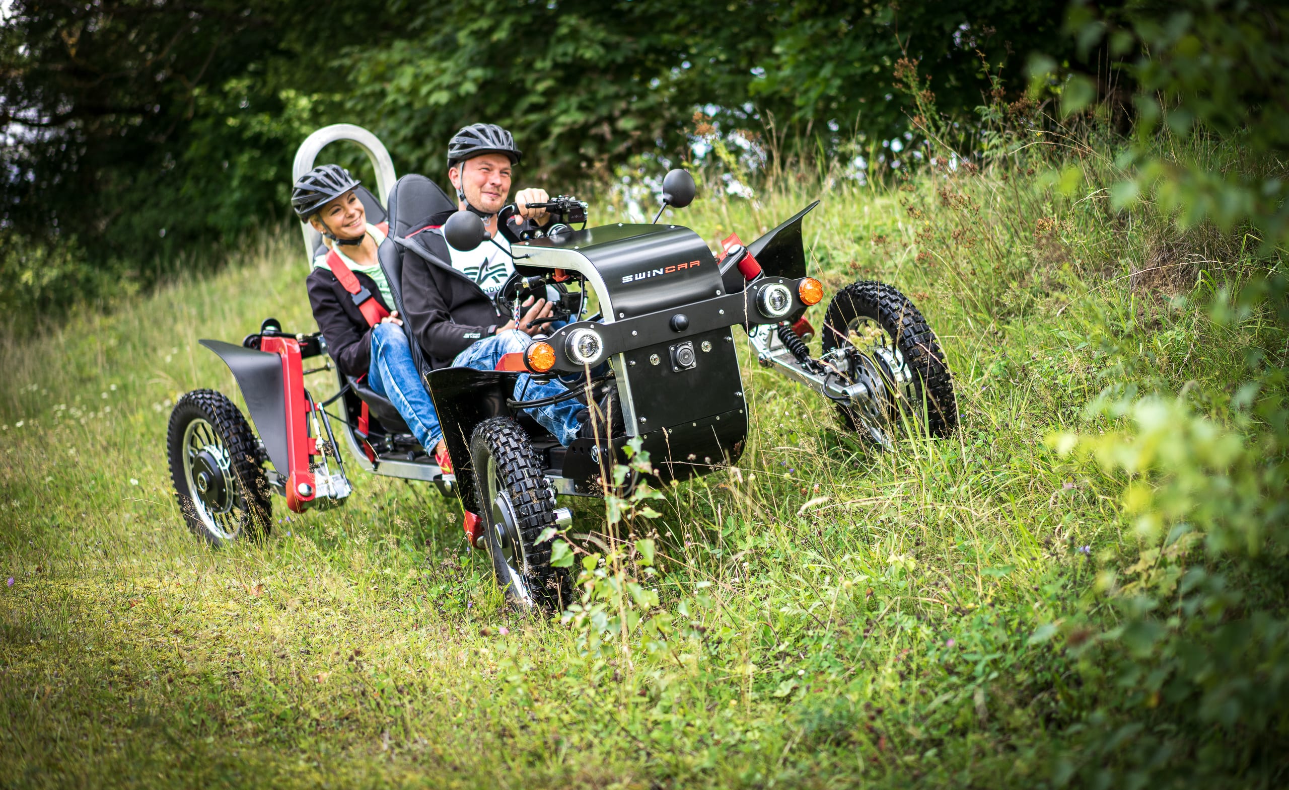 Zwei Personen fahren Geländefahrzeug im Grünen.